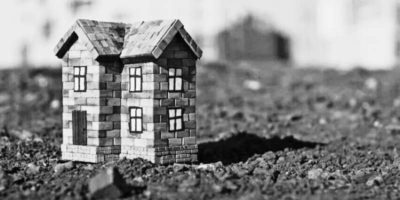 The image showcases a miniature building on some dirt land.