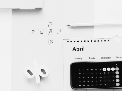 Black and white image of an Iphone calculator and folder stating tax plan.