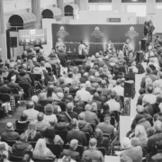 Black and white image on conference panel debate with large audience seated