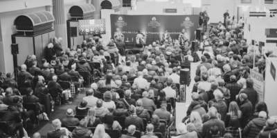 Black and white image on conference panel debate with large audience seated