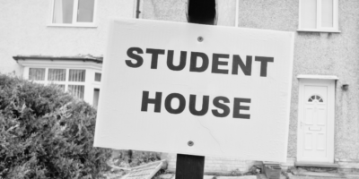 Black and white image of board outside residential house stating Student House