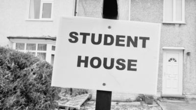 Black and white image of board outside residential house stating Student House